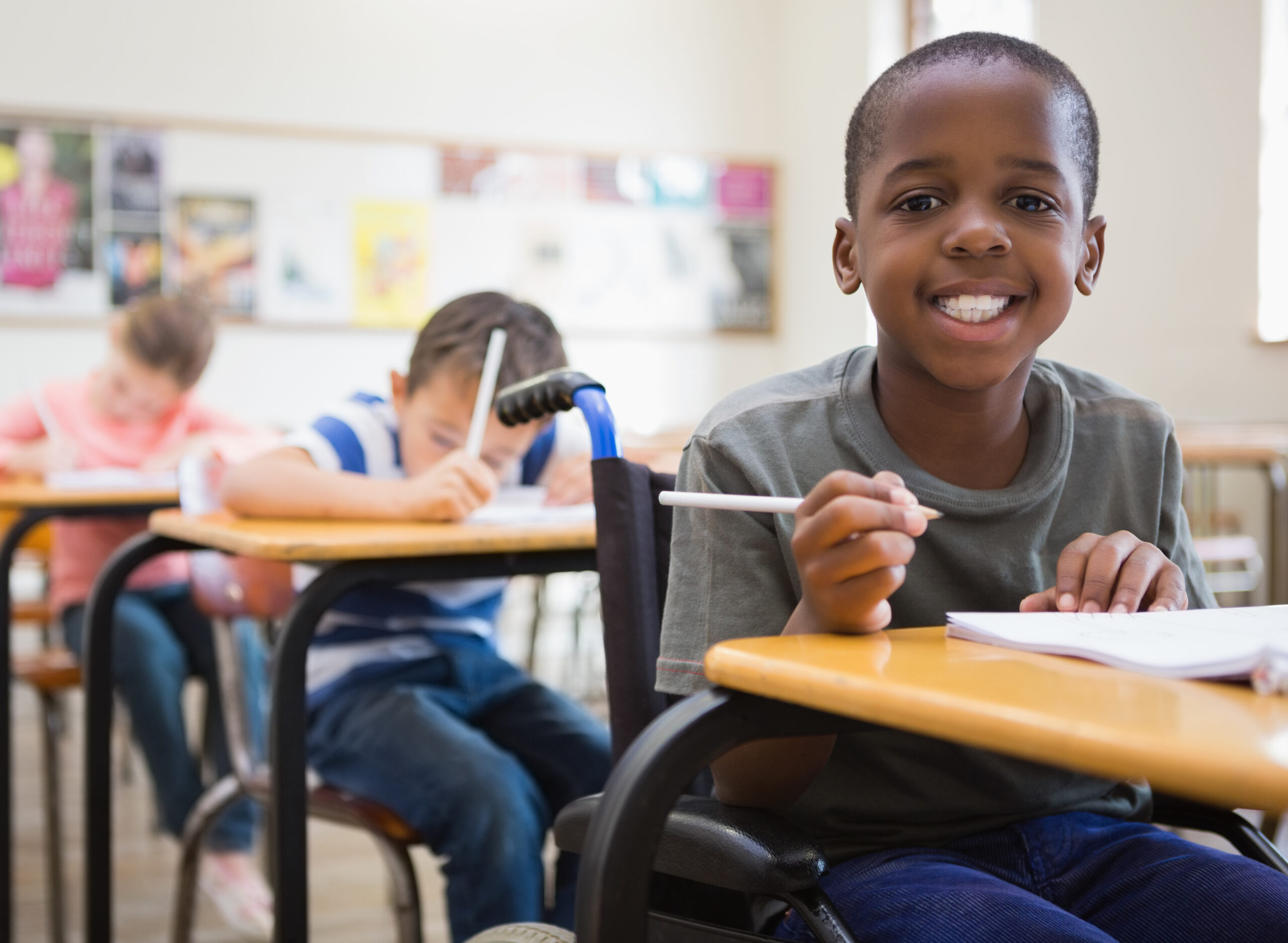 Disabled,pupil,smiling,at,camera,in,classroom,at,the,elementary